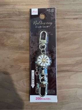 Daiso Gold Reel Key Holder with White Floral Accent